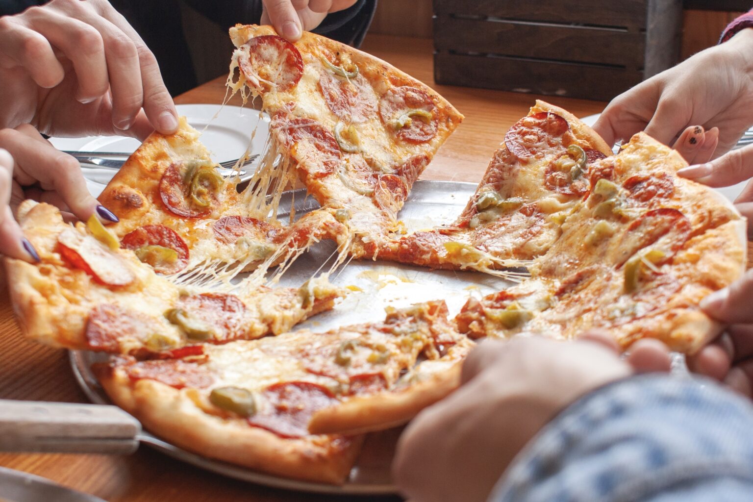 group of students friends eat Italian pizza, hands take slices of pizza in a restaurant, close-up