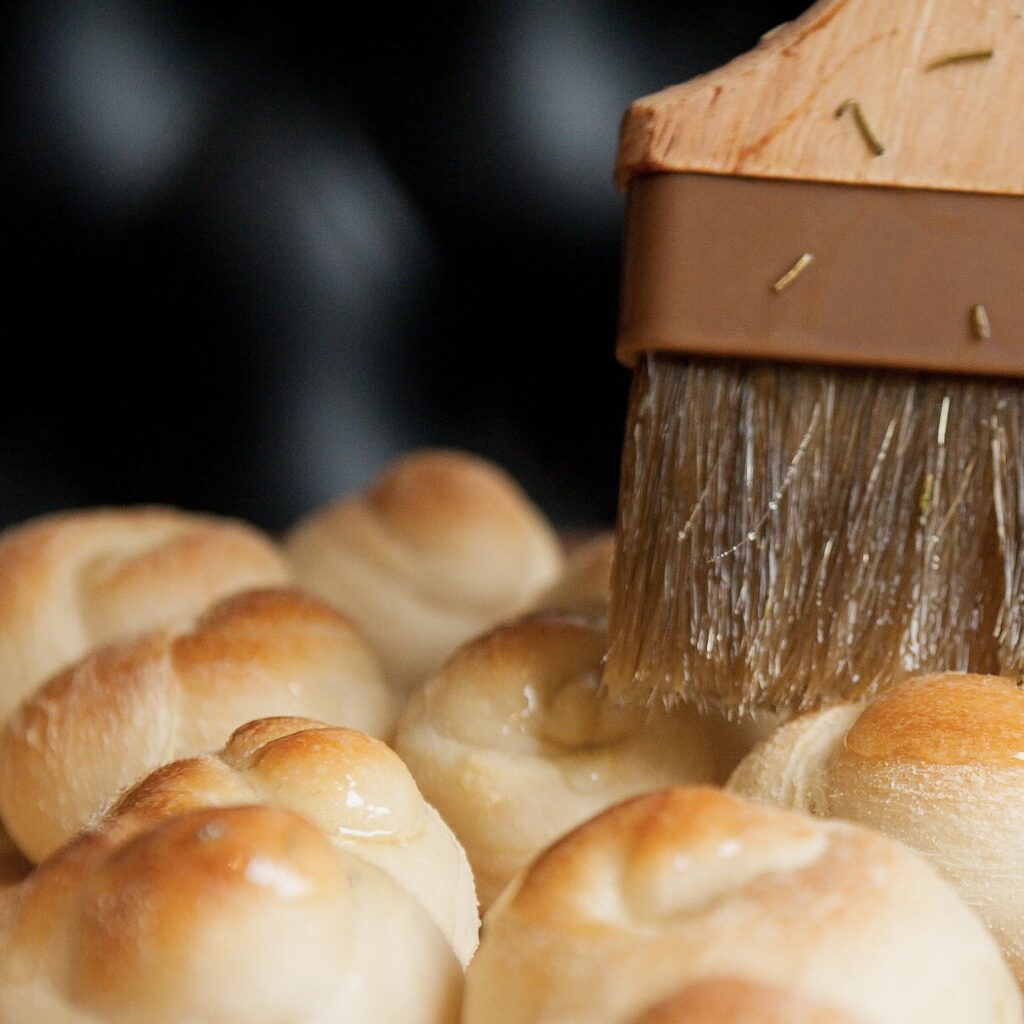 garlic knots being brushed with oil