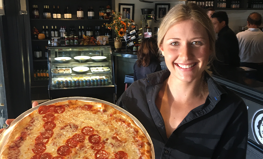 Smiling female server holding up and LA pizza