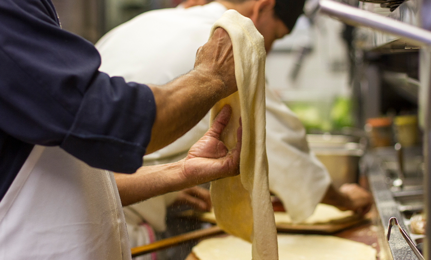 hands tossing pizza dough